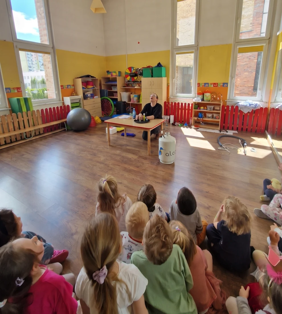Dzieci obserwują pokaz kriogeniczny w sali przedszkolnej